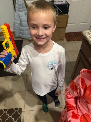 Child smiling and holding a red and yellow Raven shellblaster